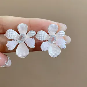 Close-up of white textured flower earrings with clear zircon center