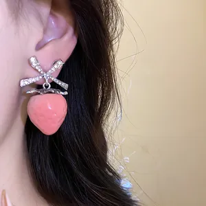 Close-up of a sweet pink strawberry earring featuring a sparkling zircon bow-knot