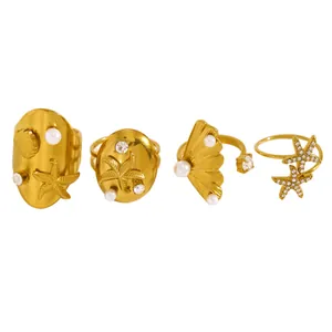 Vue détaillée de quatre bagues en acier doré avec étoiles de mer, coquillages et perles.