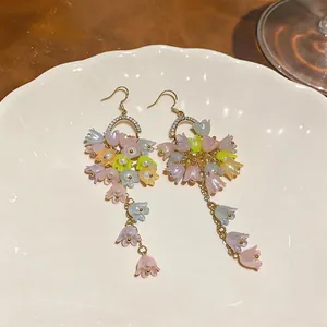 Close-up of colorful lily of the valley flower tassel earrings on white plate