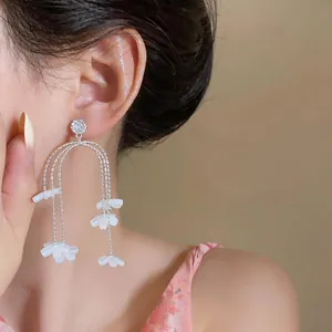 Nahaufnahme von eleganten Gänseblümchen-Quastenohrringen mit Harzblumen und Strass.