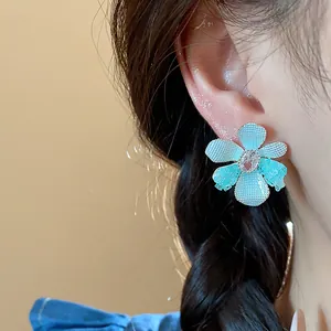 Macro detail of elegant blue glass flower stud earring featuring a zircon center stone