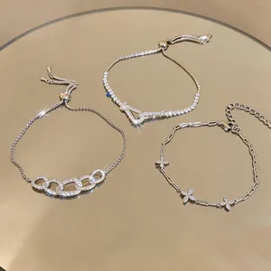 Dettaglio di tre bracciali in argento con zirconi e motivi a ferro di cavallo e fiori
