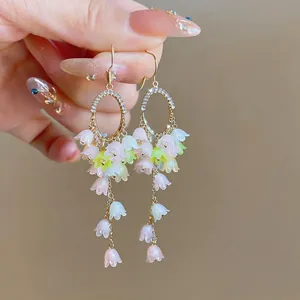 Close-up of elegant lily of the valley tassel earrings with pastel pink and white flowers