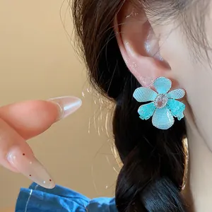 Close-up of elegant blue flower stud earring with zircon center and silver post