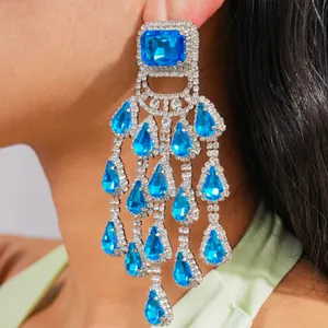 Detailed close-up of luxury oversized light blue crystal chandelier tassel earrings worn by model.
