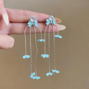 Detailaufnahme von hellblauen Gänseblümchen-Quastenohrringen mit eleganten Strasssteinen