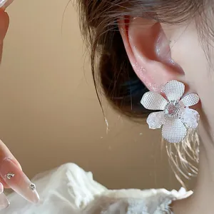 Close-up of elegant silver needle zircon glass flower stud earrings worn on ear for detail view