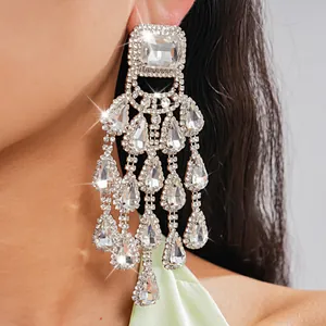 Close-up detail of oversized rhinestone chandelier earrings with teardrop tassels.
