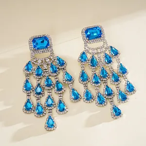 Detailed view of blue square and water drop tassel earrings with glittering rhinestones