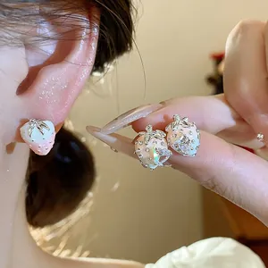 Detailed close-up of cute pink and white oil-dripping strawberry stud earrings with stones