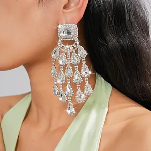 Detailed view of oversized silver rhinestone chandelier earrings with teardrop tassels.