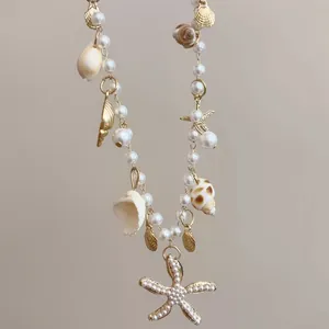 Dettaglio di una collana con stelle marine, conchiglie e perle dorate per le vacanze.