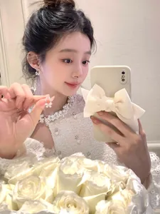 Detailed view of elegant sparkling bow-shaped pearl earrings shown on an Asian model