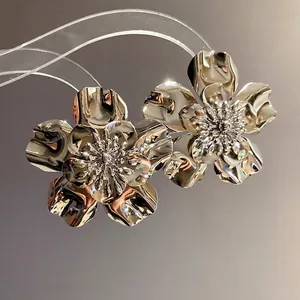Glossy silver metal flower stud earrings with a vintage textured oversized design