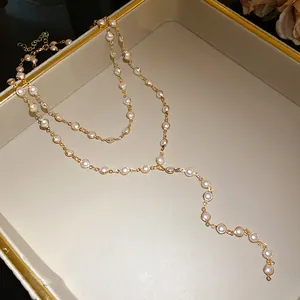 Detail view of gold-tone double-layered necklace with white beads in a jewelry box