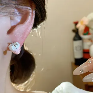 Detailed close-up showing a delicate pink gradient strawberry stud earring worn on ear