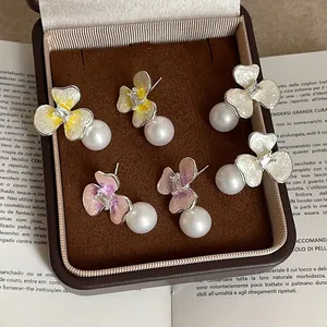 Detalle de pendientes de flores y perlas en amarillo, lila y blanco en estuche