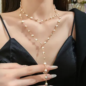 Close-up detail of a layered gold necklace with elegant white acrylic glass beads.