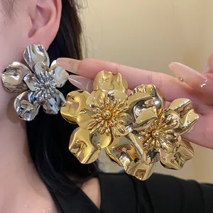 Detailed view of oversized vintage metallic flower earrings in gold and silver mirror finish