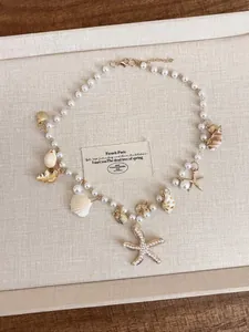 Dettaglio di collana di perle con ciondoli a stella marina e conchiglie per vacanza