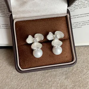 Vista detallada de elegantes pendientes de flores y perlas en estuche de lujo