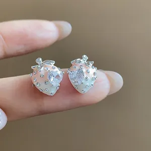 Detail view of strawberry stud earrings with pink enamel and heart cubic zirconia.