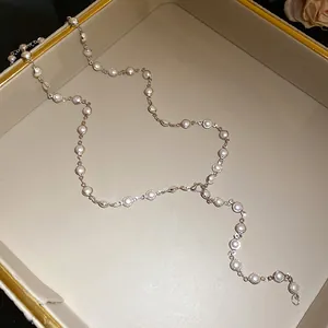 Detail view of an elegant acrylic pearl necklace with silver links on a beige jewelry tray