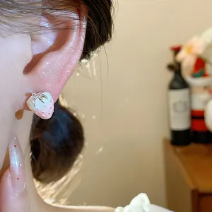 Close-up view of a pink and white strawberry stud earring worn on a model's ear