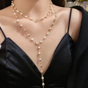 Close-up of an elegant layered gold-tone Y-necklace featuring acrylic glass pearls.