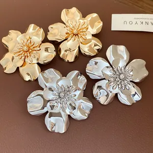 Macro shot of shiny metallic flower stud earrings in gold and silver finish