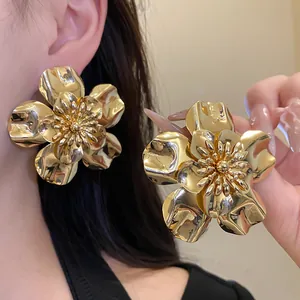 Detail of oversized vintage gold flower stud earrings with a glossy metallic finish.