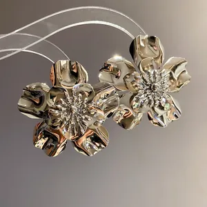 Detailed macro shot of high-shine metallic flower stud earrings with intricate petals.