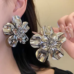 Close-up detail of metallic glossy flower stud earrings with vintage silver finish