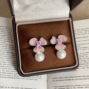 Elegantes pendientes de flores rosas con perla blanca en un joyero marrón de alta calidad
