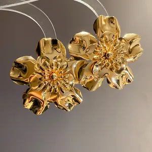 Close-up of glossy golden metal flower earrings featuring intricate layered petals.