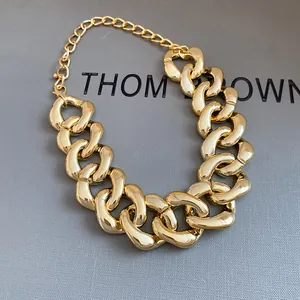 Detailed view of chunky gold-plated adjustable chain necklace on grey textured box