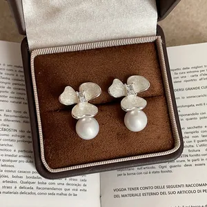 Primer plano detallado de elegantes pendientes de flores y perlas en un joyero de terciopelo