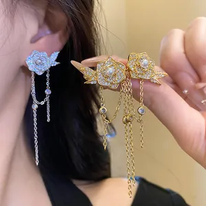 Detail of 18K gold plated rose earrings with pearls, zircons and delicate chain tassels