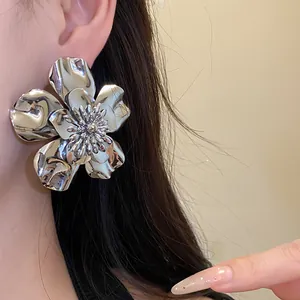 Macro close-up showing the intricate shiny silver metal flower earring worn on model ear