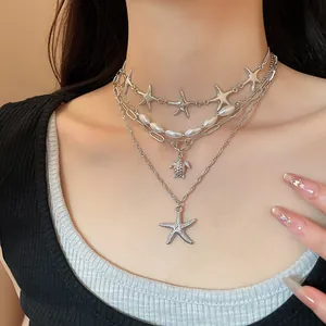 Detailed view of a multi-layered silver necklace featuring starfish and turtle pendants
