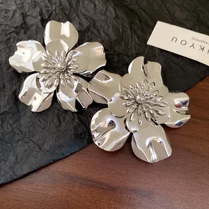Close-up of vintage metallic silver glossy flower earrings with layered 3D petal design