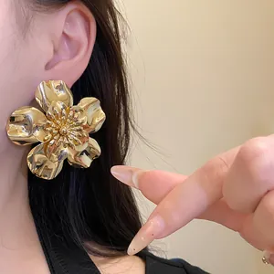 Detailed macro view of oversized gold metallic flower earrings with glossy finish