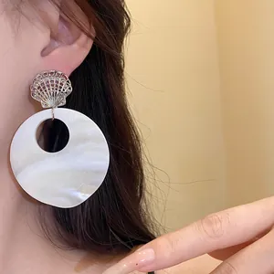 Elegante Muschelohrringe mit Perlmutt-Anhänger an einem asiatischen Model im Detail