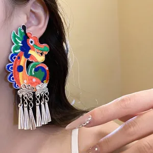 Chinese style dragon embroidery drop earrings with silver tassels shown on ear.