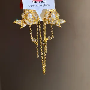 Close-up of 18K gold-plated rose earrings with zircon pavé and pearl tassels