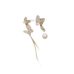 Elegant asymmetric butterfly tassel earrings with pearl drop on white background