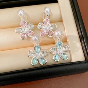 Primo piano di eleganti orecchini a fiore con perle e cristalli in un portagioie