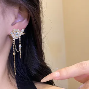 Close-up of golden flower tassel earring with pearl and zirconia detail on model
