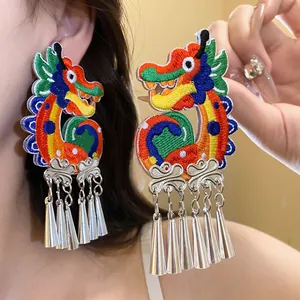 Close-up of colorful embroidered dragon clip-on earrings with silver tassels